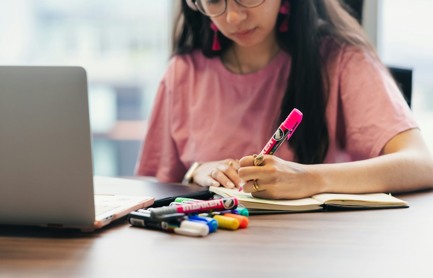 A student writing study notes beside a laptop